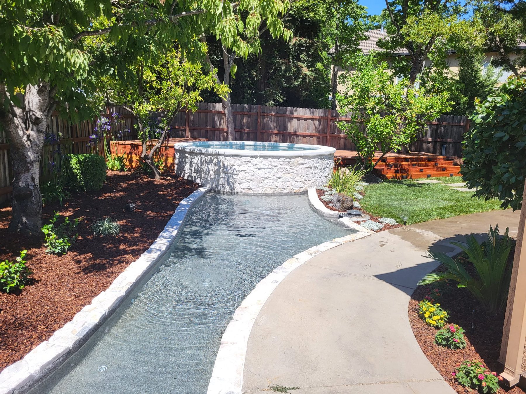A finished backyard by AJ Construction: a spa, a broom-finished concrete walkway and new landscaping on a property near Placerville, California